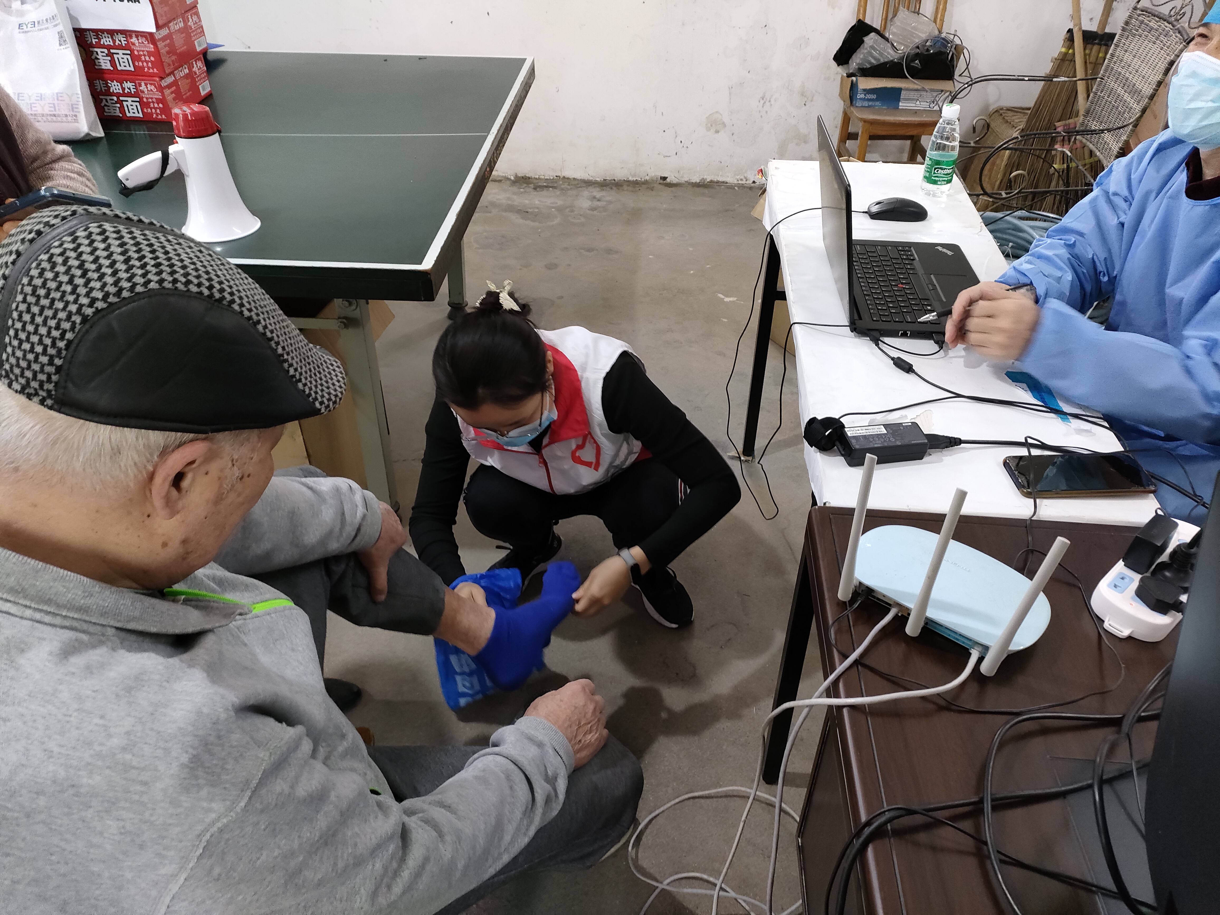武江人社服务队志愿者为黄大爷脱下鞋袜给医生检查 摄影：骆雪花.jpg