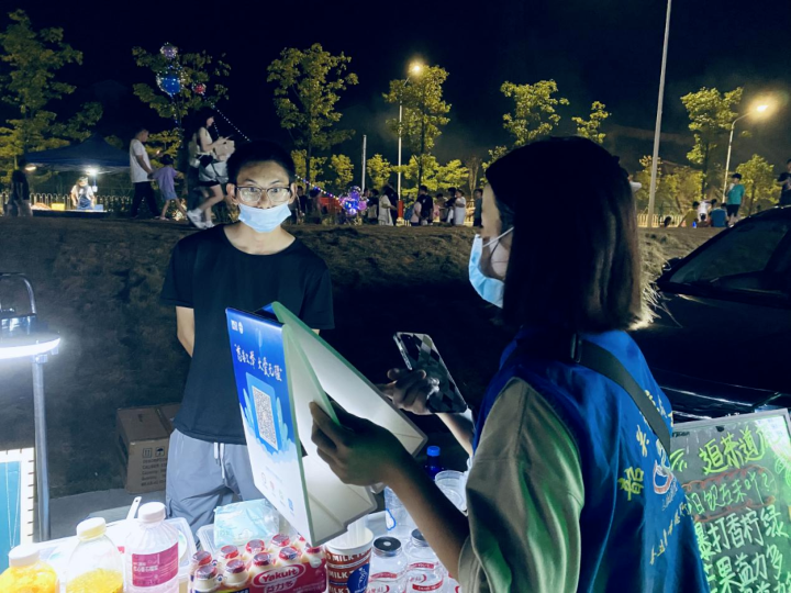 韶关市立德会志愿者向摊主介绍义卖活动.png